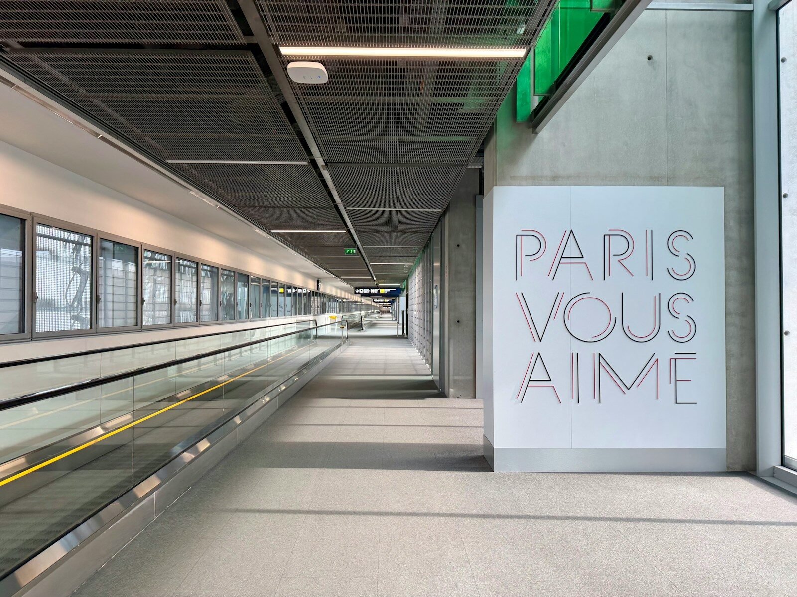 Modern airport walkway with "paris vous aime" art